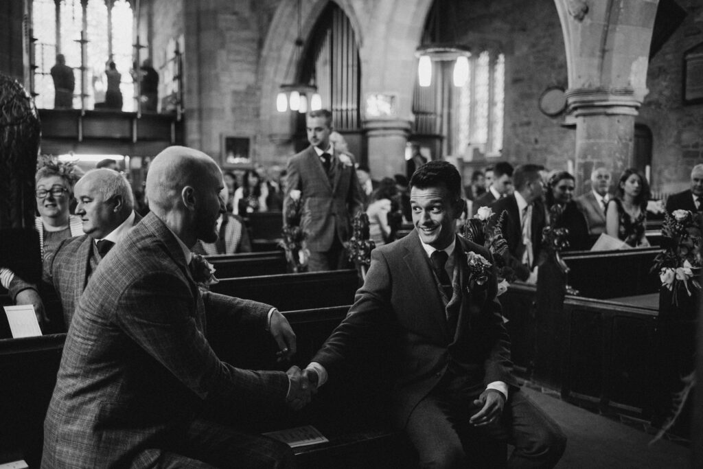 groom shaking hands with his dad in church