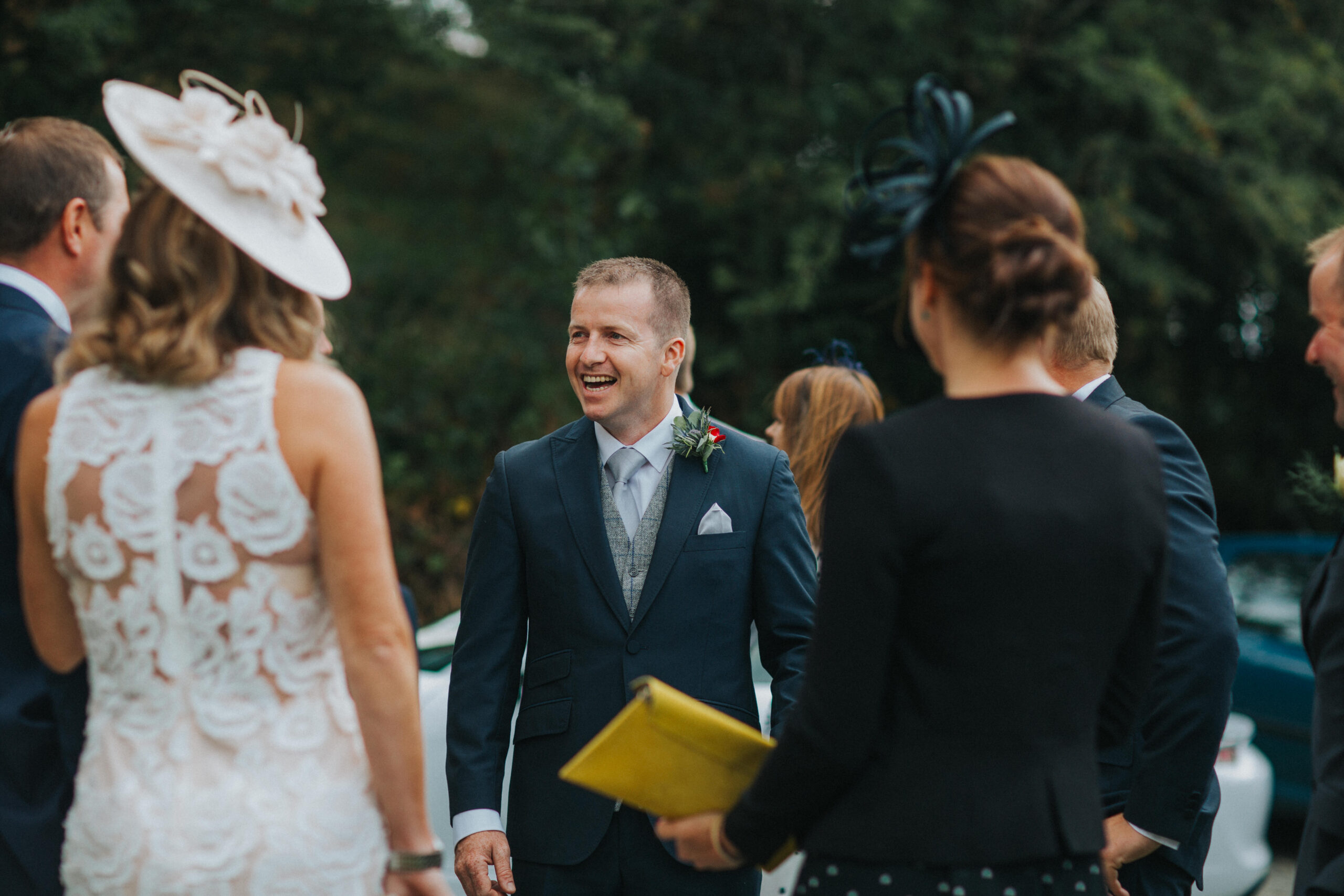 groom laughing with guests outside church