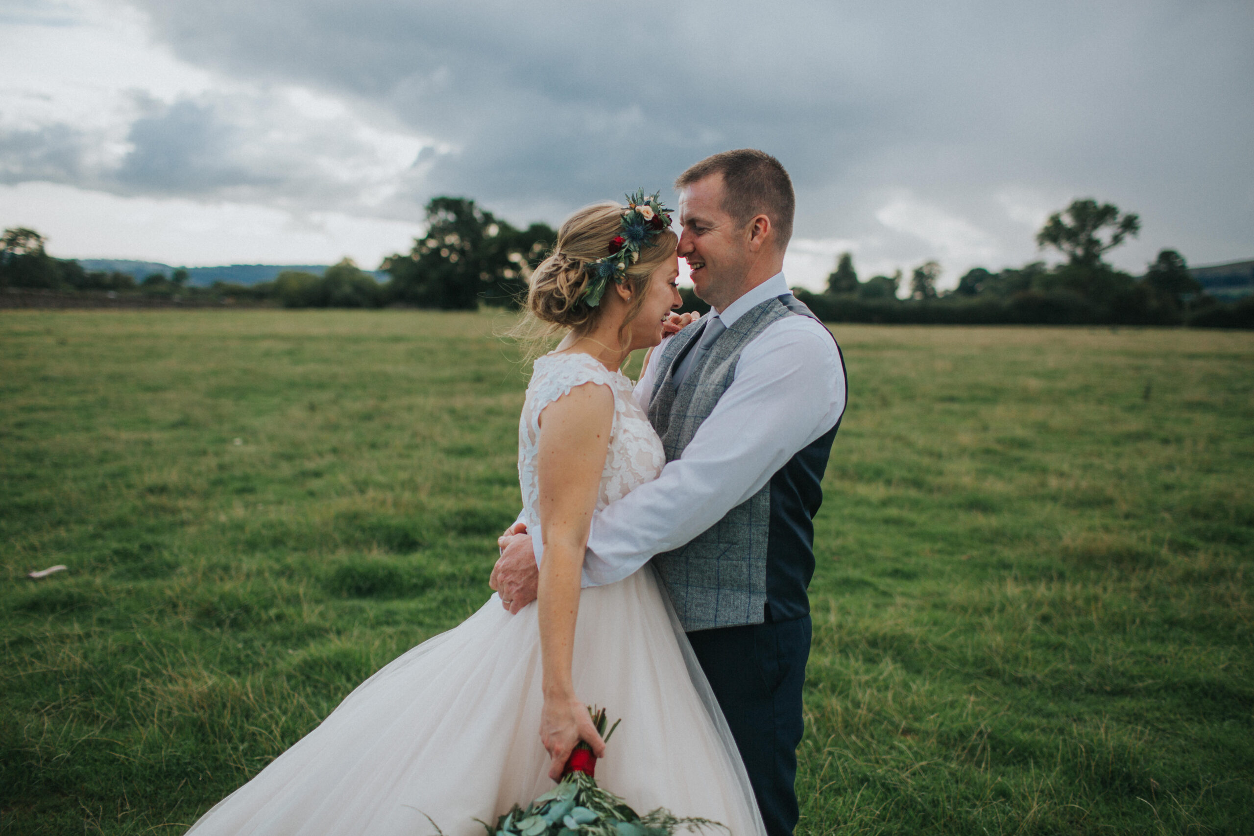 bride and groom embracing in a field