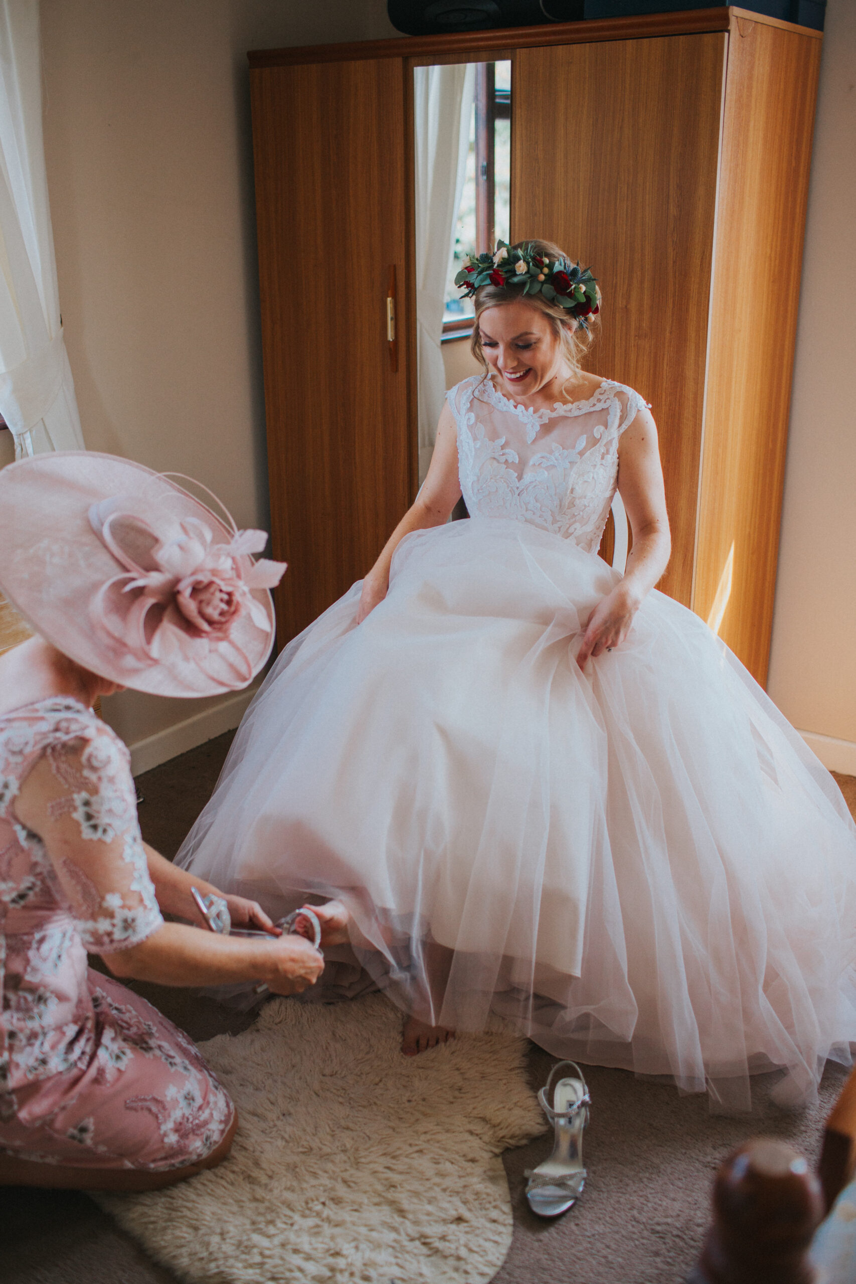bride's mum helping her put her wedding shoes on
