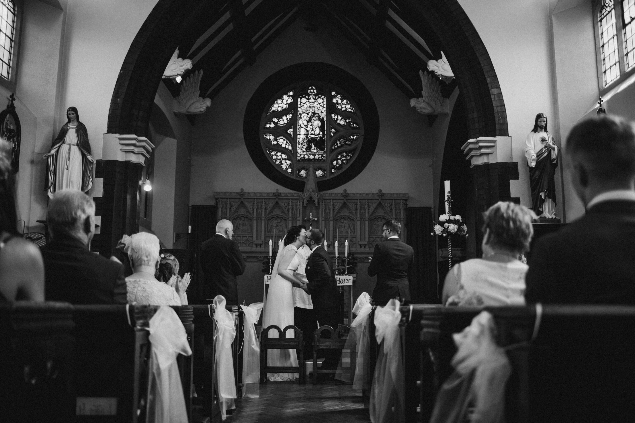 black and white image of bride and groom's first kiss at church