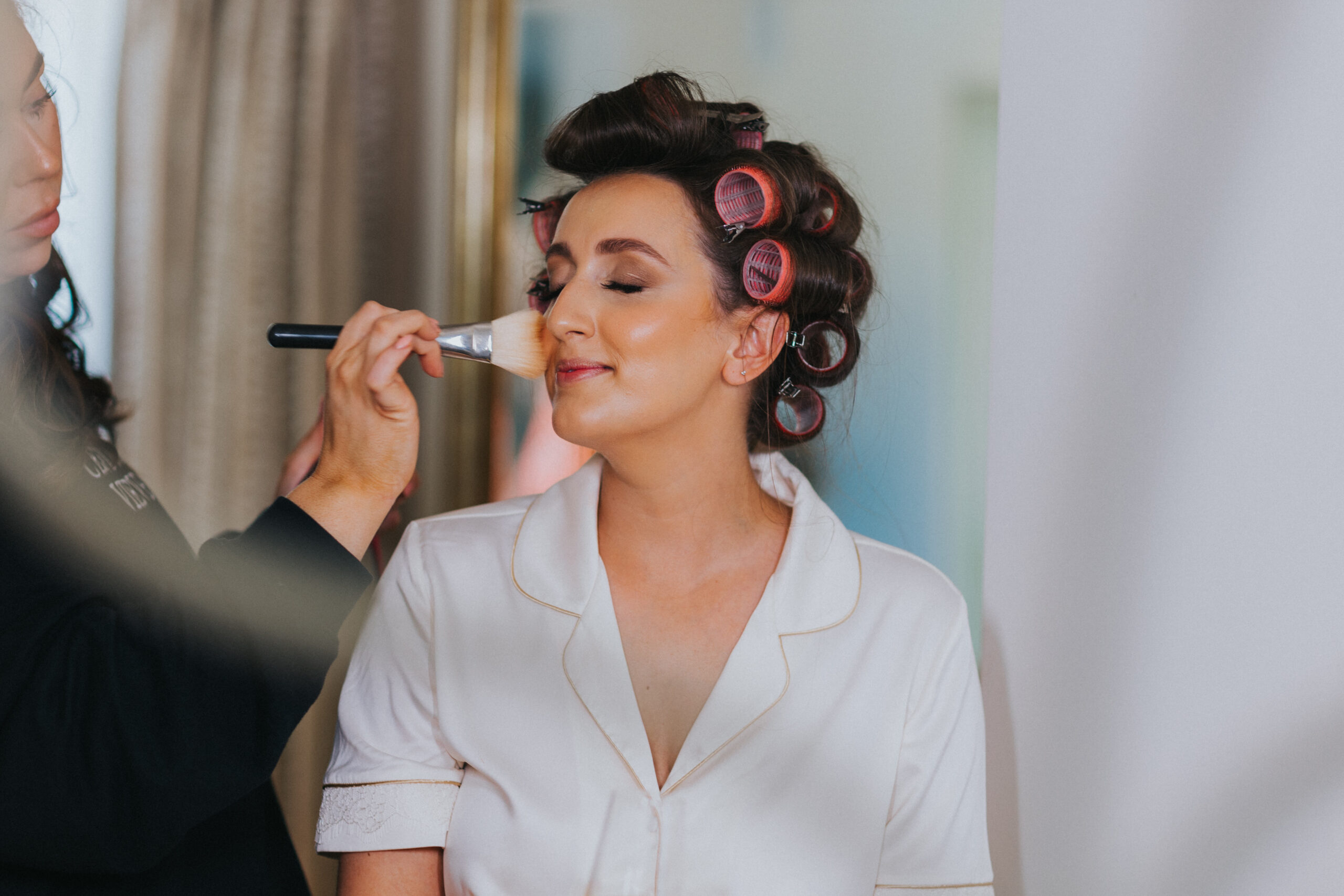 bride having make up done, hair in rollers