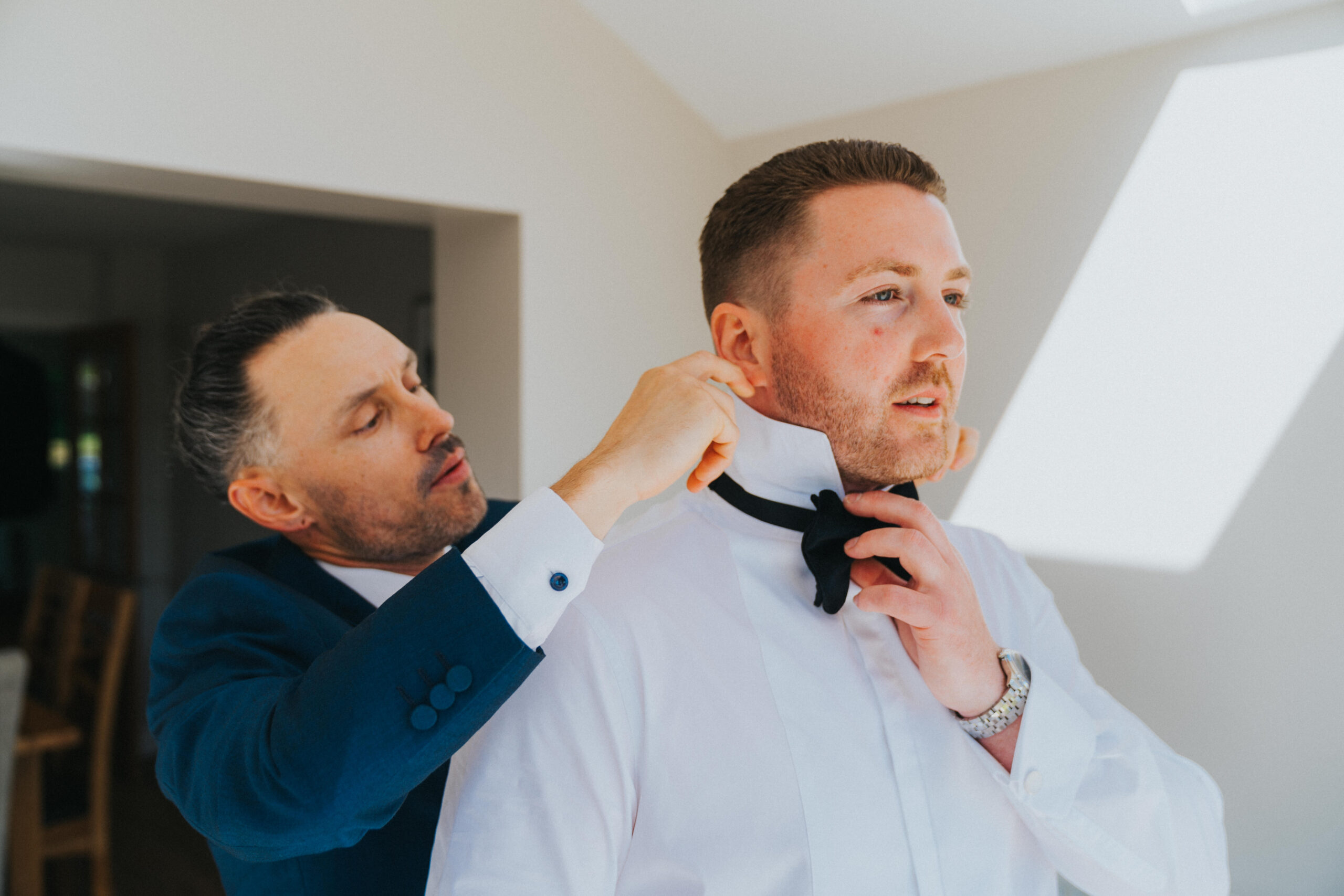 groom being helped with bow tie