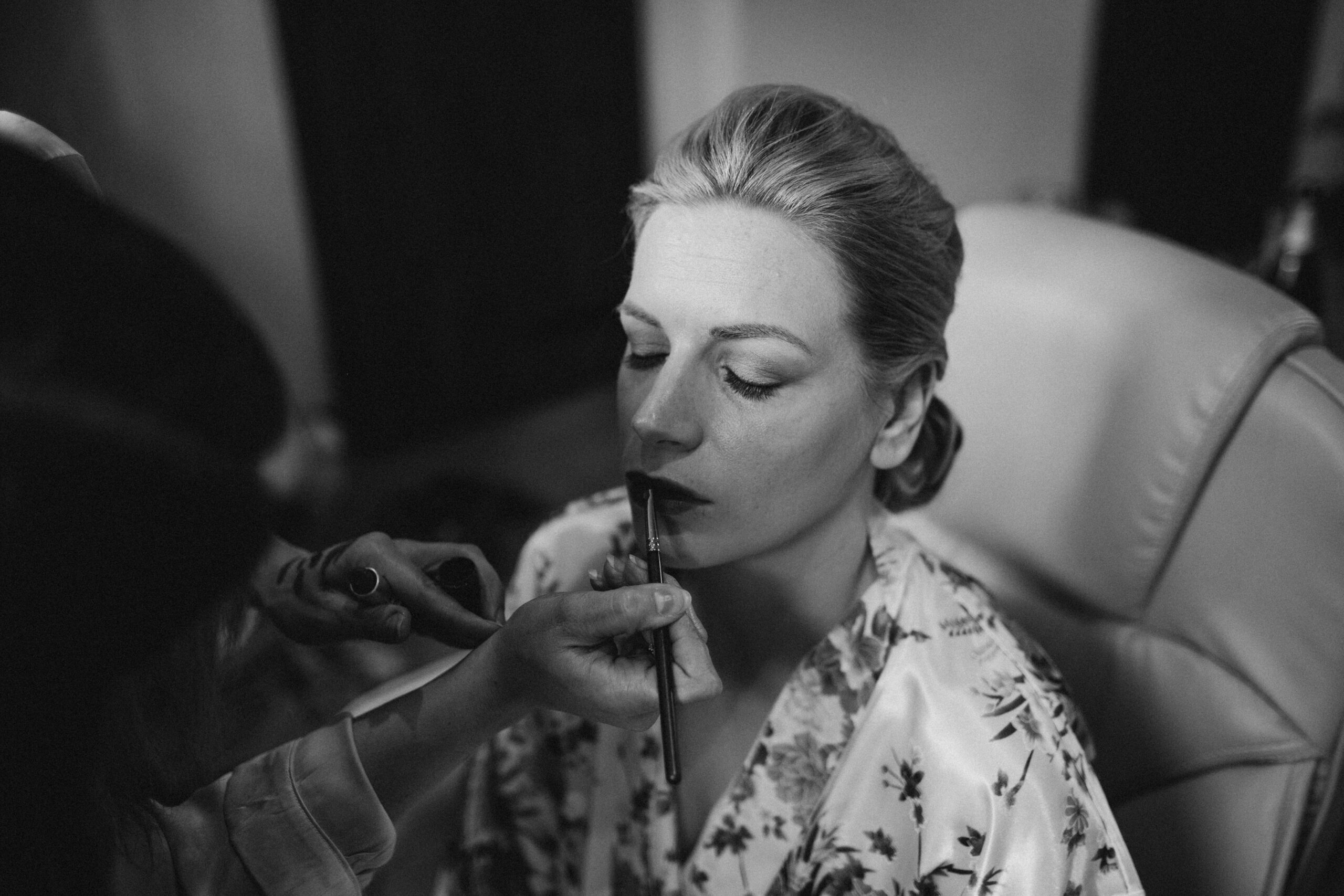 black and white photograph of bride having lipstick applied