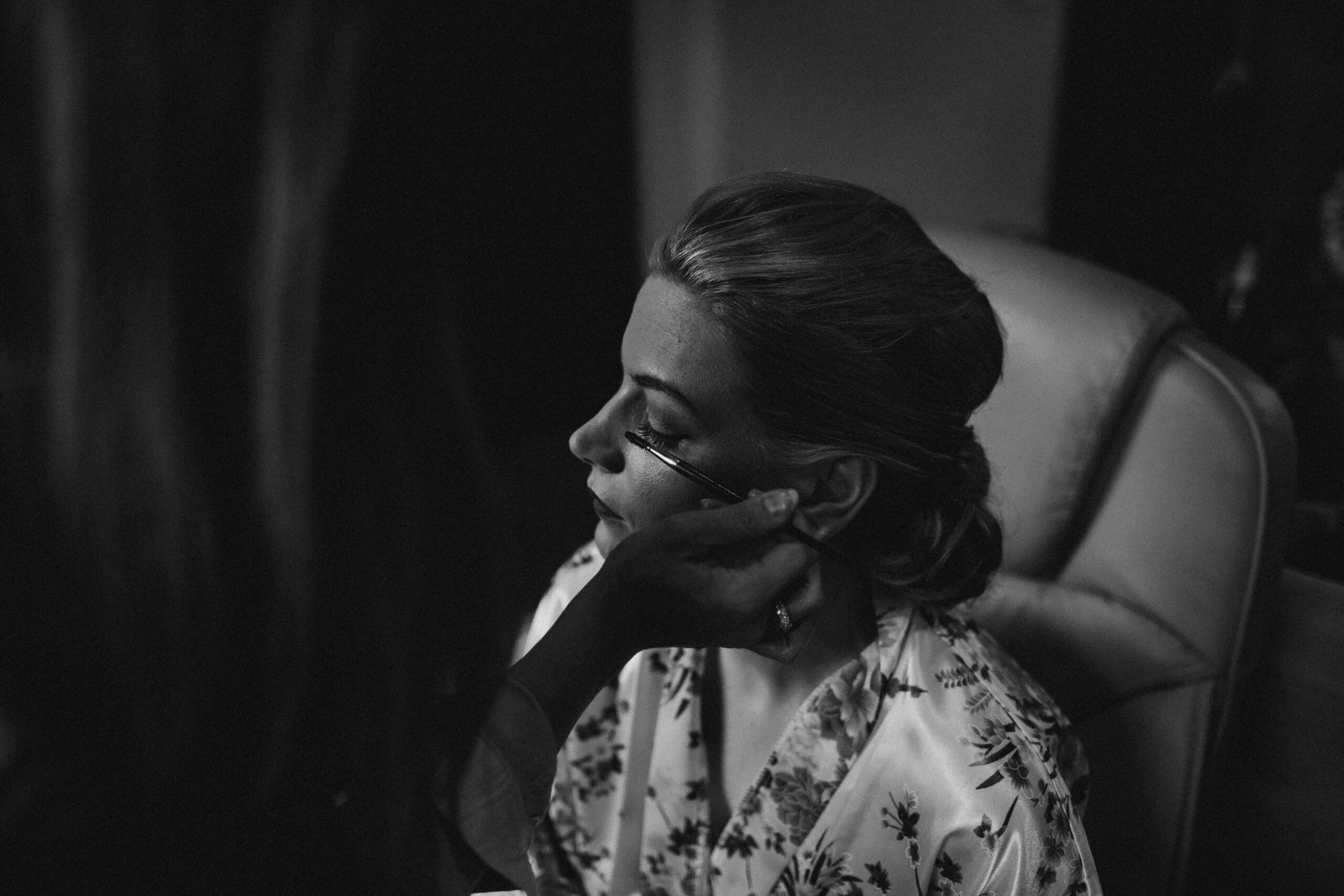 black and white photograph of bride having mascara done