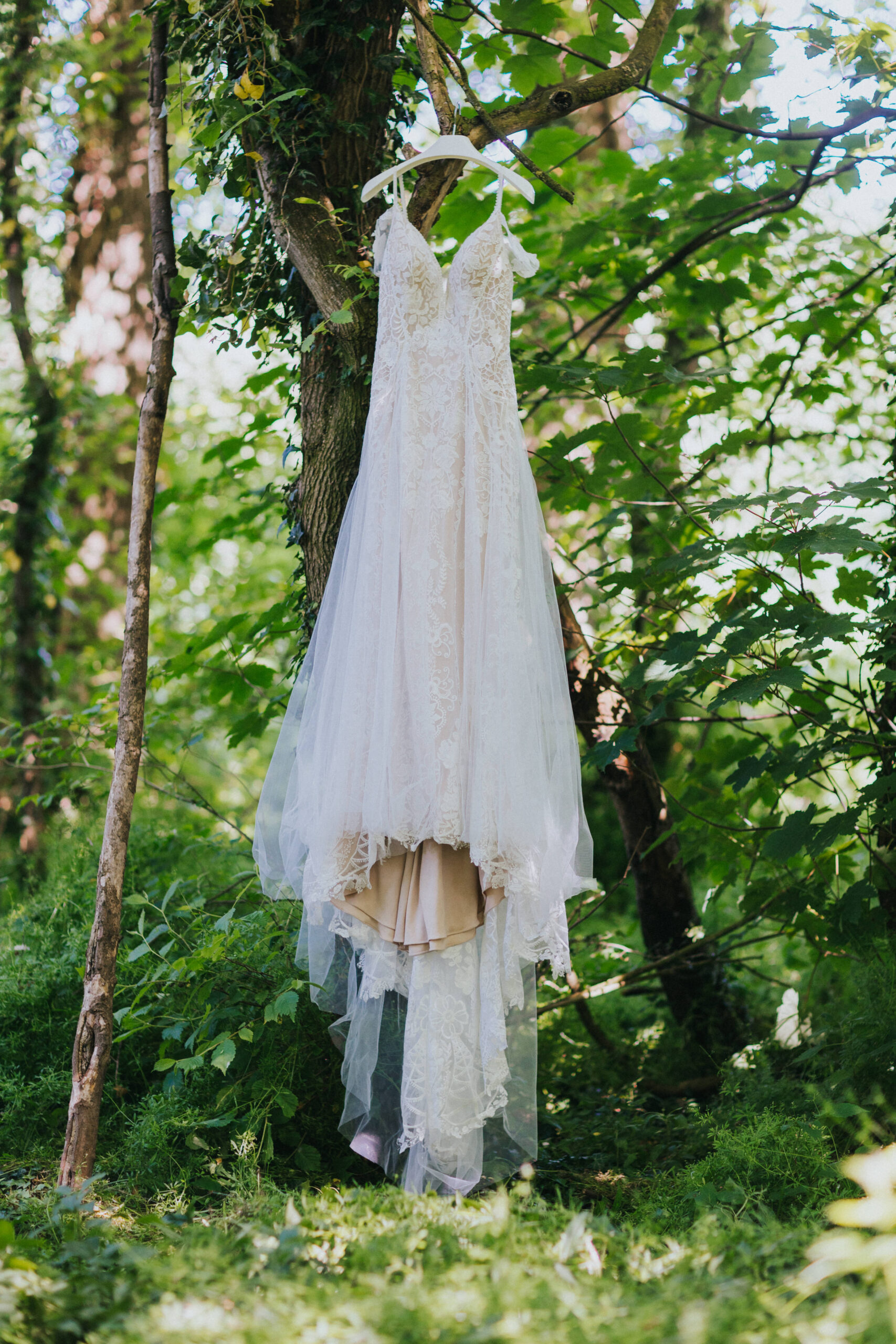 wedding dress hanging in woodland