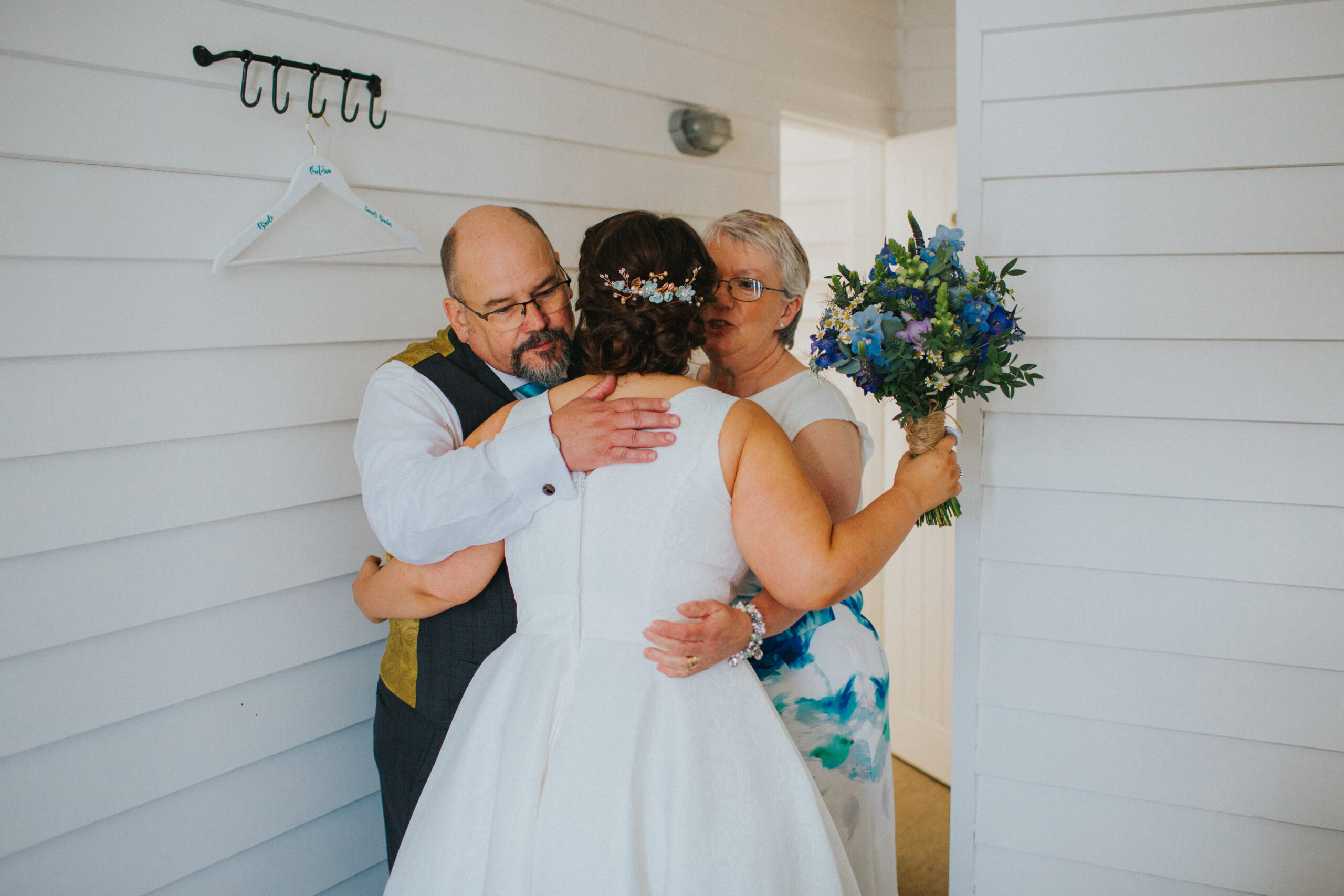 bride mum and dad hugging bride