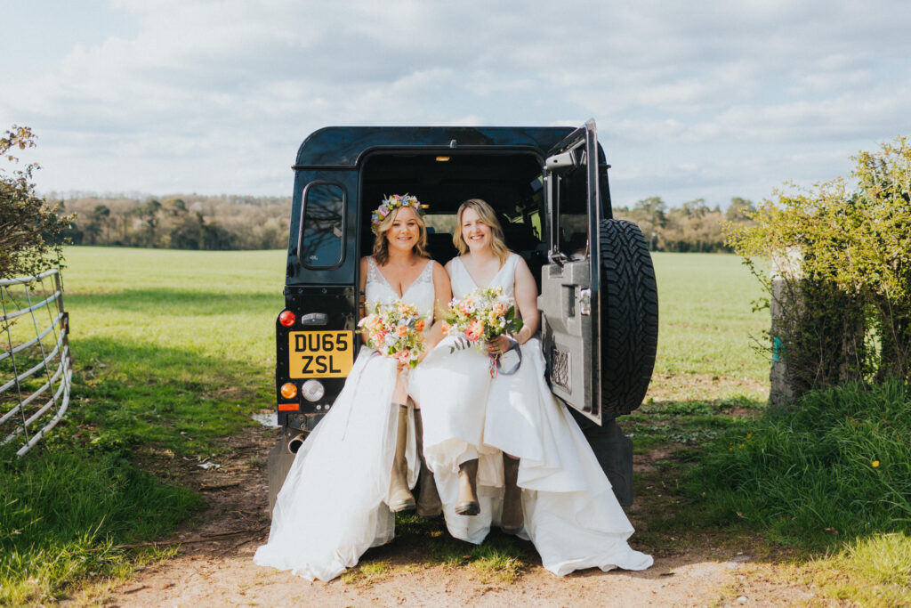 two brides in a landrover wearing wellies
